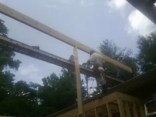 Carpenter setting a ridge beam over a new addition frame — Ice Dam Removal by Roofing Brothers in Keno