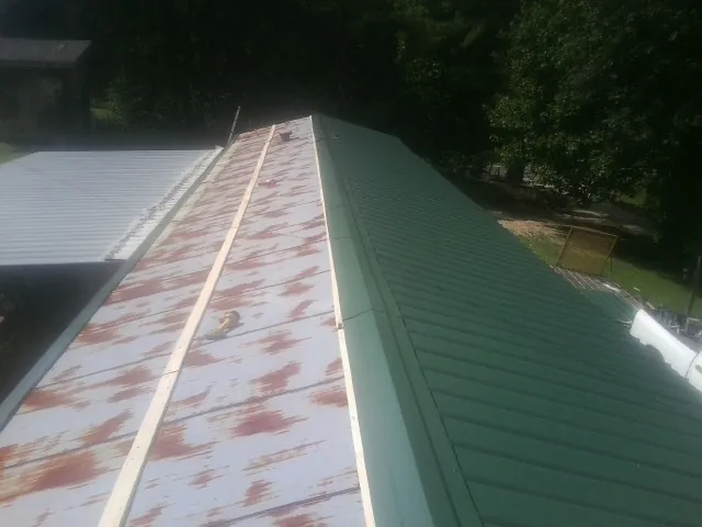 Old rusted panels beside newly installed green metal roofing — Wind Damage Roof Repair by Roofing Brothers in Keno