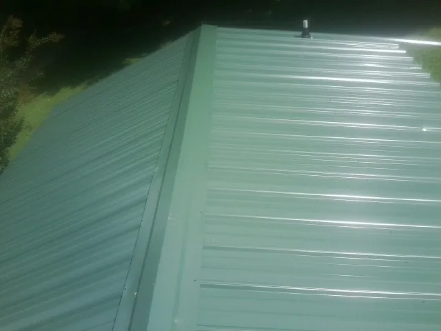 New green metal panels meeting at the ridge of a roof — Flat Roof Repair work by our crew in Keno