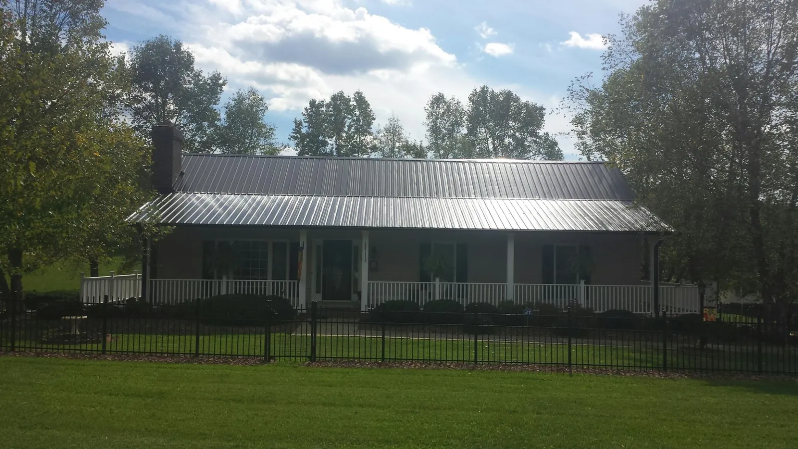 Gray metal roof on a brick ranch with a full width front porch — Gutter Guard Installation work by our crew in Keno