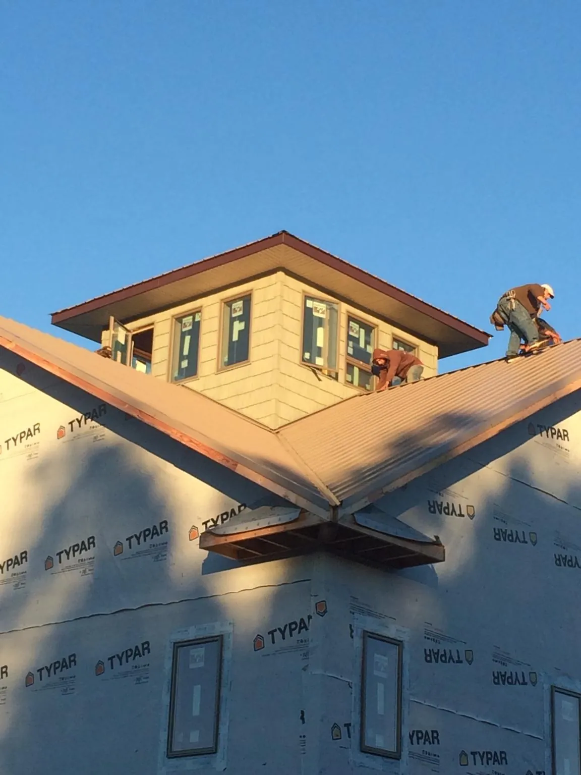 Roofers working around a rooftop cupola on a new metal roof at sunset — Roof Waterproofing in Keno by Roofing Brothers